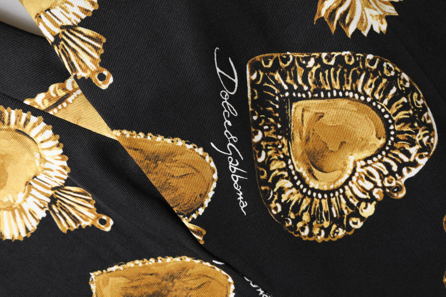 Pantalones con estampado de corazón sagrado en dorado y negro de Dolce & Gabbana